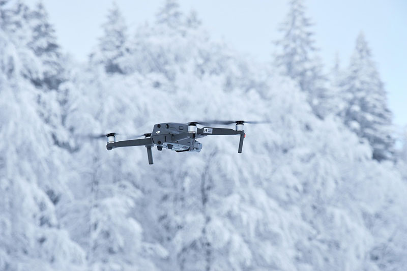 Image of drone flying over snowy forests