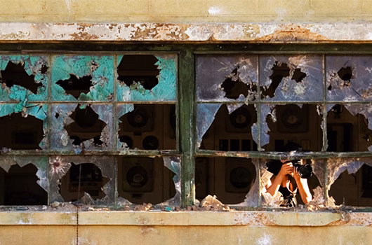 Journalist in bombed out building taking photos