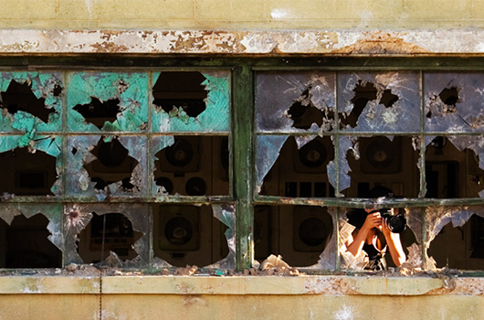 Journalist in bombed out building taking photos